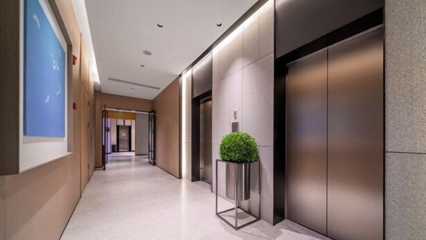 A modern hallway with a marble floor, a potted plant, and a wall-mounted elevator. - JI Hotel (Chongqing North Railway Station) (Chongqing)