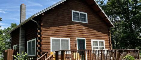 A log cabin with a wooden deck and a chimney.