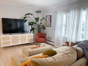 Relax in this stylish living room with a flat-screen TV, comfortable armchair, and plush sofa.
