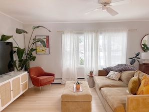 Relax in this inviting living room with a TV, comfortable sofa, and a cozy armchair.