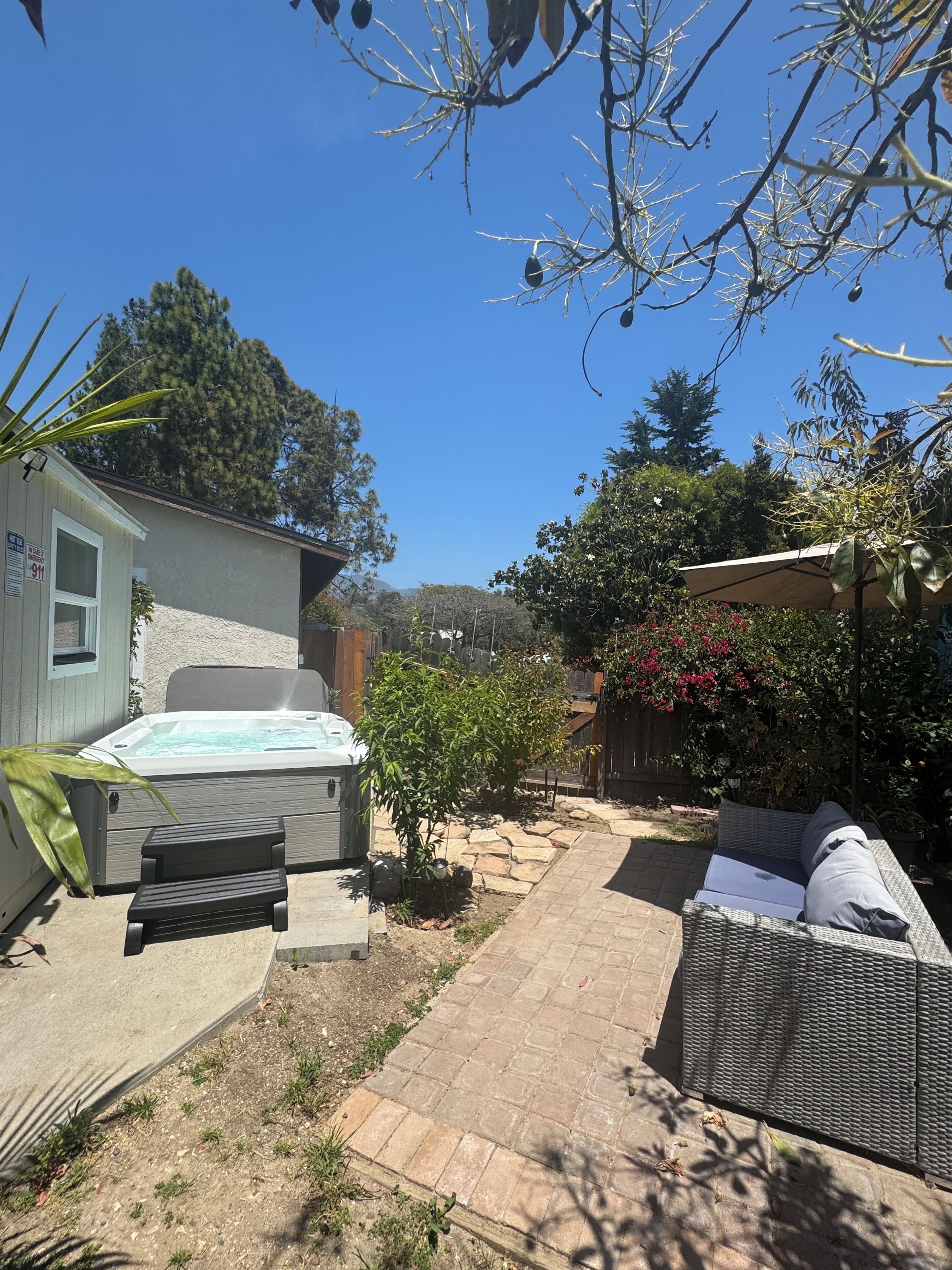 A backyard with a hot tub, patio furniture, and a small garden.
