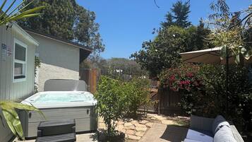 A backyard with a hot tub, patio furniture, and a small garden.