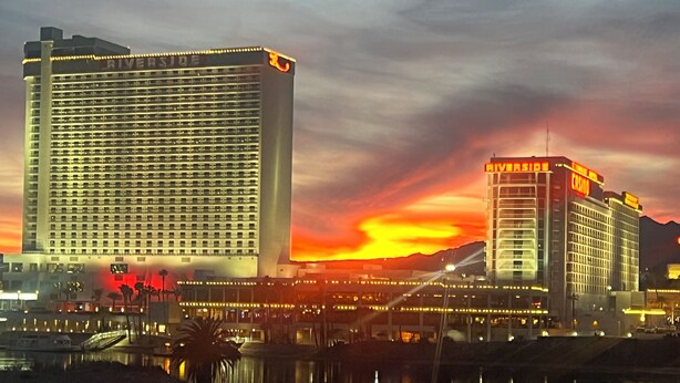 A large hotel with a prominent Riverside sign, multiple floors, and a view of the sunset over a body of water. - Cozy Farmhouse Style - Pet Friendly (Bullhead City)