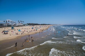 A beach with a lifeguard tower, umbrellas, and people enjoying the water.