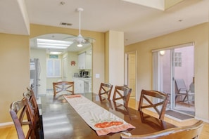 A dining area with a long table, chairs, and a ceiling fan.