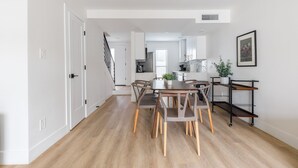 A modern kitchen with white cabinets, a central island, and a dining area with a wooden table and chairs. - Quiet 2BR - 10 Min Walk to Old Town (Scottsdale)