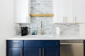 A modern kitchen with white cabinets, a blue countertop, and a stainless steel dishwasher.