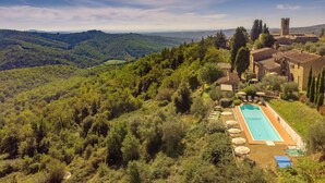Une villa avec piscine, entourée d’une végétation luxuriante et de collines.