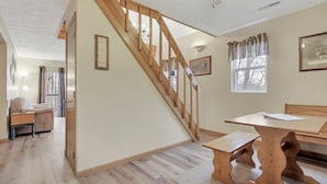 A room with a wooden staircase, a dining table, and a bench. - Gray Manor (Hocking Hills Area) (Rockbridge)