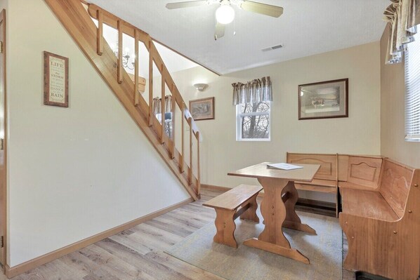 A room with a wooden staircase, a wooden bench, a table, and two framed pictures on the walls. - Gray Manor (Hocking Hills Area) (Rockbridge)
