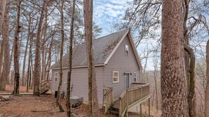 A cabin with a wooden deck, surrounded by trees. - Gray Manor (Hocking Hills Area) (Rockbridge)