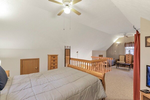 A bedroom with a single bed, a wooden dresser, a desk, and a chair.