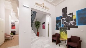 Ein modernes Interieur mit einer Marmortreppe, roten Ohrensesseln und einer Wand mit abstrakter Kunst.