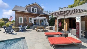 A house with a pool, outdoor seating, and a covered patio area.