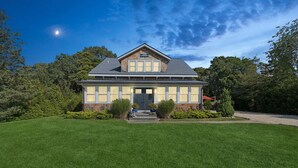 A two-story house with a front porch, a well-maintained lawn, and a clear sky.
