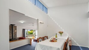 Un coin repas avec une table dressée pour deux personnes, une cheminée en pierre et une vue sur l’extérieur.