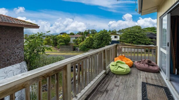 Une terrasse en bois avec deux fauteuils en forme de sac, une vue sur un quartier résidentiel et un ciel dégagé.