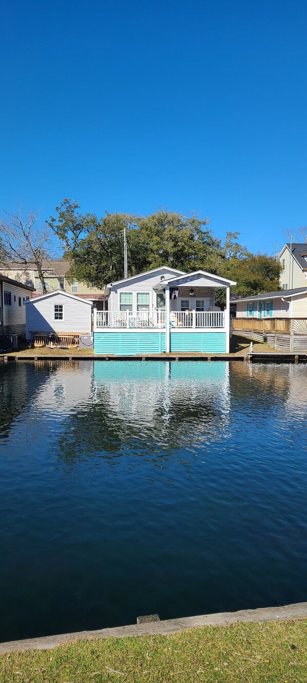 A houseboat with a porch and windows, floating on a body of water. - Ocean Lakes Beach Cottage N-114 on Lake Near Store & Waterpark (Myrtle Beach)