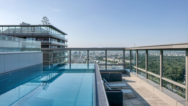Une piscine à débordement située sur le toit, offrant une vue sur la ville, un design architectural moderne et un espace de détente en plein air.