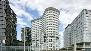 Un immeuble moderne à plusieurs étages, doté d’une façade incurvée, et entouré d’autres constructions contemporaines.