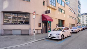 Un edificio con insegne che indicano 'BAR', 'LOUNGE SIGARI' e 'STEAKHOUSE', oltre a una targa 'BEAT-N'. Auto parcheggiate lungo la strada.