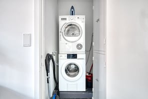A laundry room with two stacked washing machines and a hose. - Modern Langstrasse 2.5 Room w/ Storage, 5 mins to Tram, by Blueground (Zurich)
