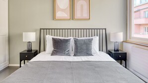 Una camera da letto con un letto, due comodini, due lampade e due opere d'arte astratte appese alle pareti.