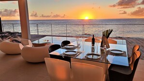 Vista al atardecer desde una terraza con una mesa preparada para dos, con vista al mar.