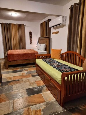 A bedroom with two wooden beds, a wall-mounted air conditioner, and a tiled floor. - Cozy tropical paradise- 1min from the beach! (Río Grande)