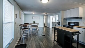 Cozinha moderna com área de refeições, piso de madeira e eletrodomésticos embutidos.