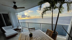 Een balkon met een houten tafel, stoelen, een bank en een bloempot.