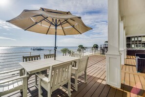 Enjoy a serene waterfront view from this deck with a table and chairs, shaded by an umbrella.