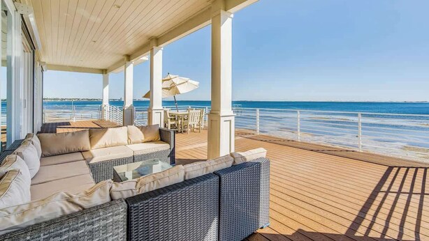A covered outdoor deck with a wicker sofa, a table, and an umbrella.