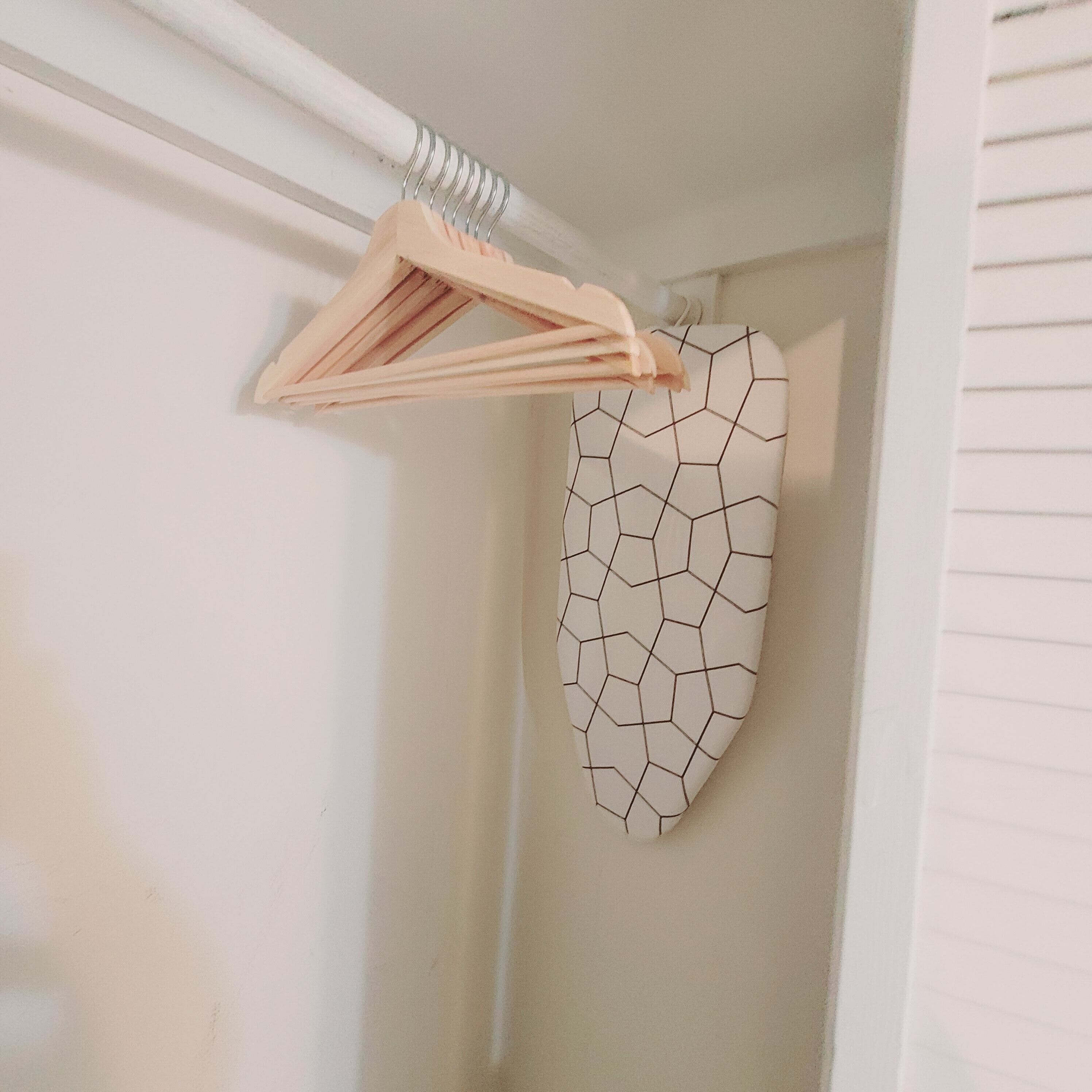 Esquina de una habitación con una pared blanca y una prenda colgante de estampado geométrico.