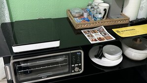 Un coin cuisine avec un plan de travail noir, une machine à café, une bouilloire et un plateau contenant des aliments.
