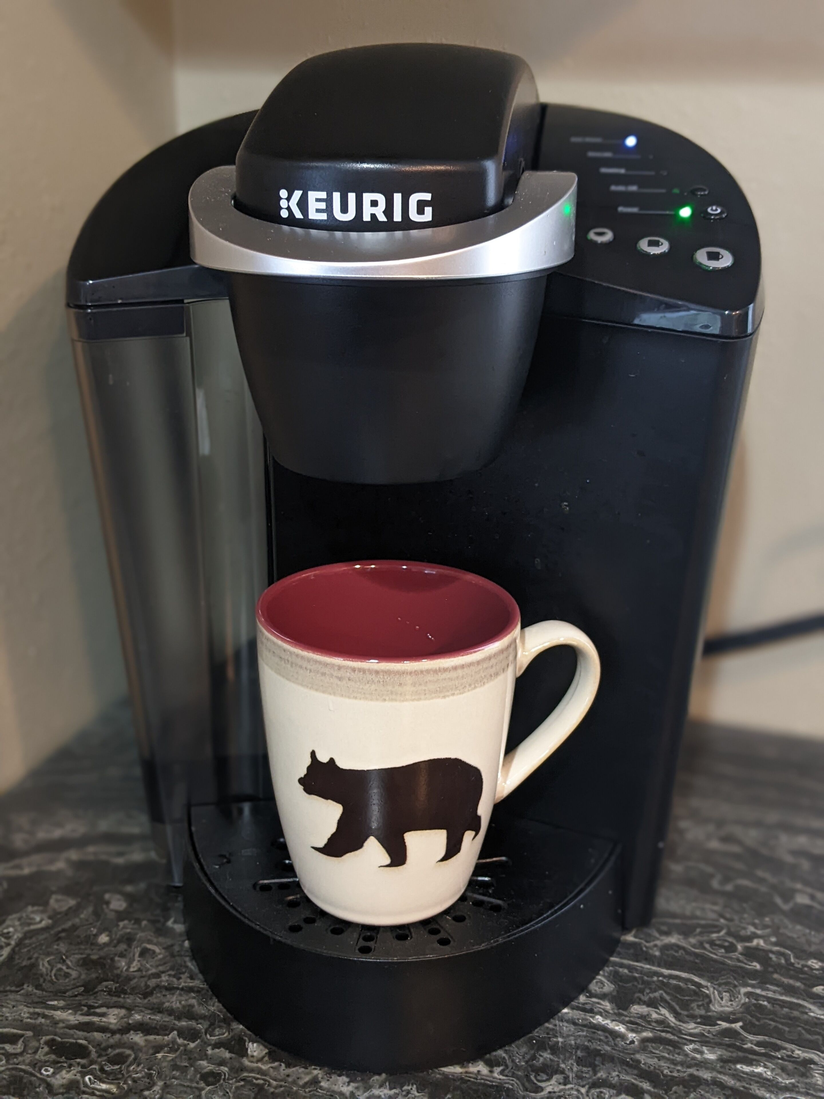 A Keurig coffee maker with a mug on its drip tray.