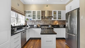 A modern kitchen with white cabinetry, a stainless steel refrigerator, and a central island. - Welcome to our charming, 2-level house just 5 min walk to 3 Sisters, Echo Point! (Katoomba)