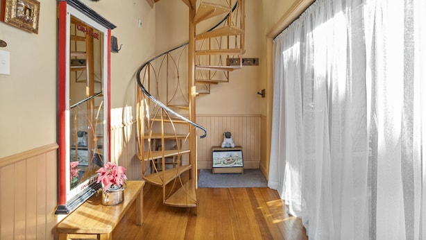 A spiral staircase in a room with wooden flooring, a bench, a small table with a vase of flowers, and a framed picture on the wall. - Welcome to our charming, 2-level house just 5 min walk to 3 Sisters, Echo Point! (Katoomba)