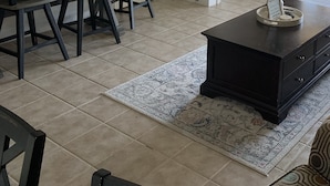 A dining area with a table and chairs, a flat-screen TV mounted on the wall, and a dark-colored coffee table with a decorative item on it. - Lovely Lake Condo with BOAT SLIP and Pool (Alexander City)
