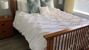 A bedroom with a wooden bed frame, white bedding, and a ceiling fan. - Lovely Lake Condo with BOAT SLIP and Pool (Alexander City)
