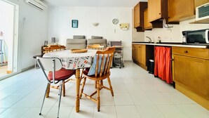 A compact kitchen with wooden cabinets, a microwave, and a dining area with a table and chairs. - 2190 LAS MURALLAS 1-1, VERY WELL LOCATED, CLOSE TO SHOPS AND THE BEACH, CIUDADELA DE ROSES AREA. (Roses)