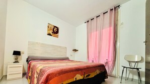 A bedroom with a bed, a nightstand, a chair, and a wall-mounted lamp. - 2190 LAS MURALLAS 1-1, VERY WELL LOCATED, CLOSE TO SHOPS AND THE BEACH, CIUDADELA DE ROSES AREA. (Roses)
