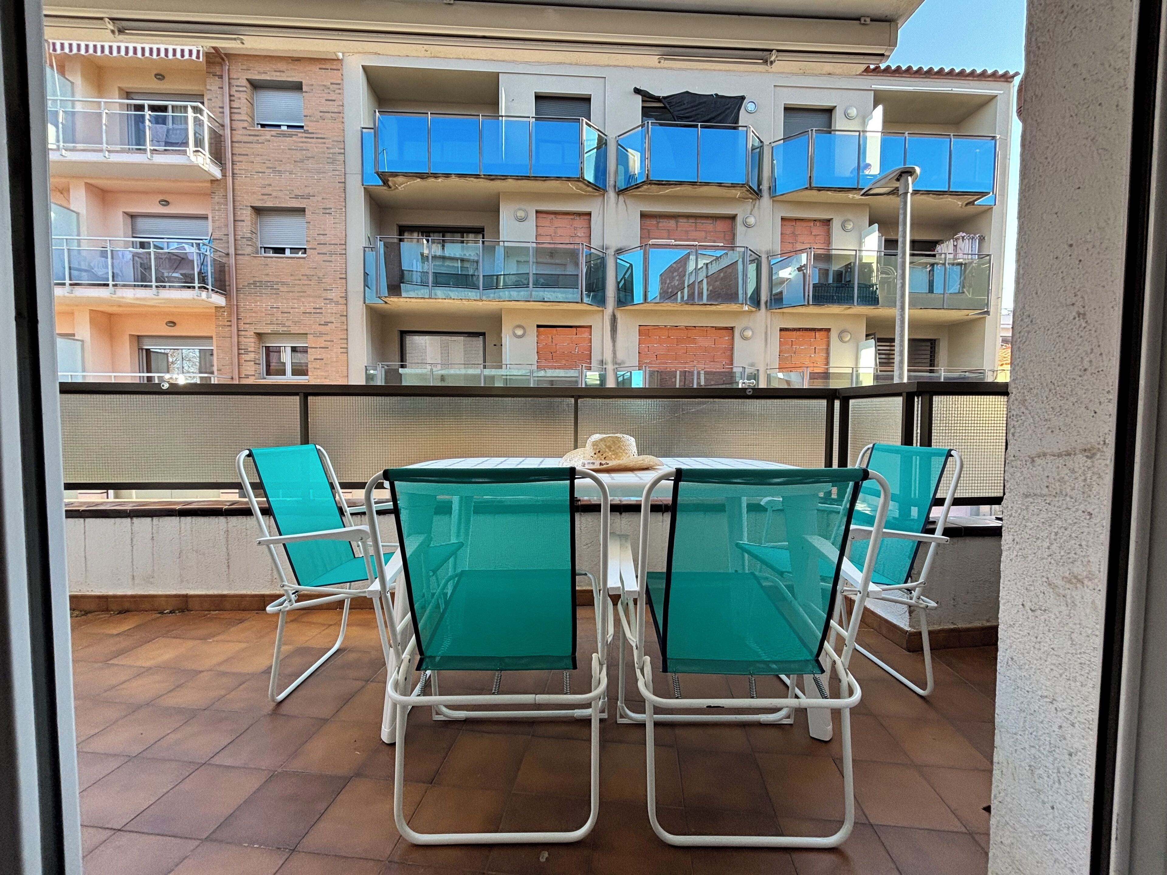 A balcony with a table and chairs, overlooking a building with multiple balconies.