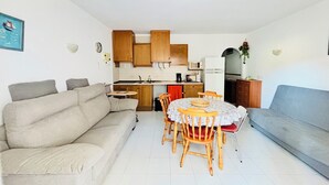 A compact living space with a sofa, dining table, chairs, and a kitchenette. - 2190 LAS MURALLAS 1-1, VERY WELL LOCATED, CLOSE TO SHOPS AND THE BEACH, CIUDADELA DE ROSES AREA. (Roses)
