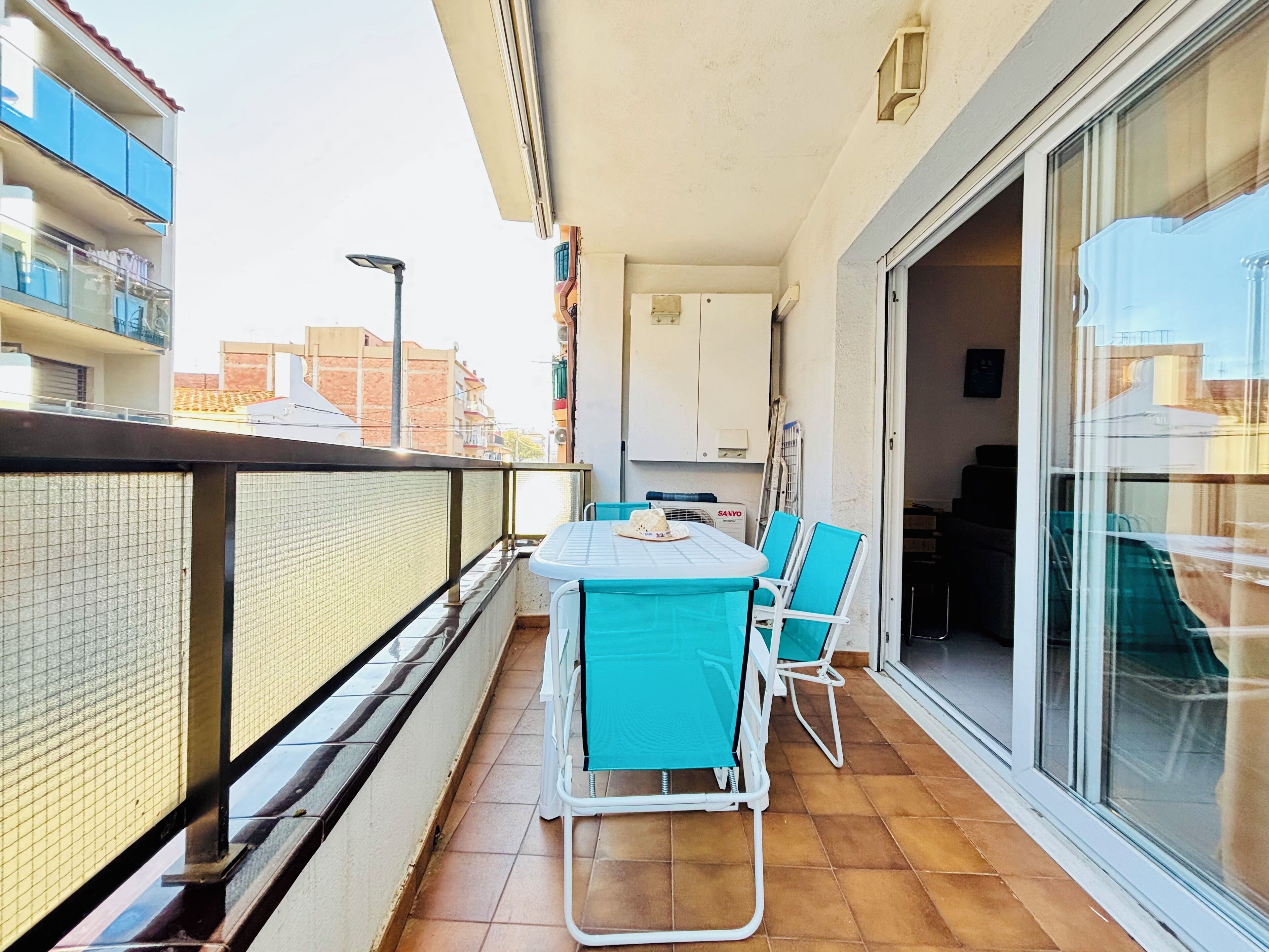 Un balcon avec une table et des chaises, une porte-fenêtre coulissante et une vue sur le paysage urbain.