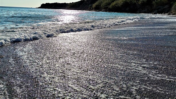 Een strand met een kiezelstrand en golven.