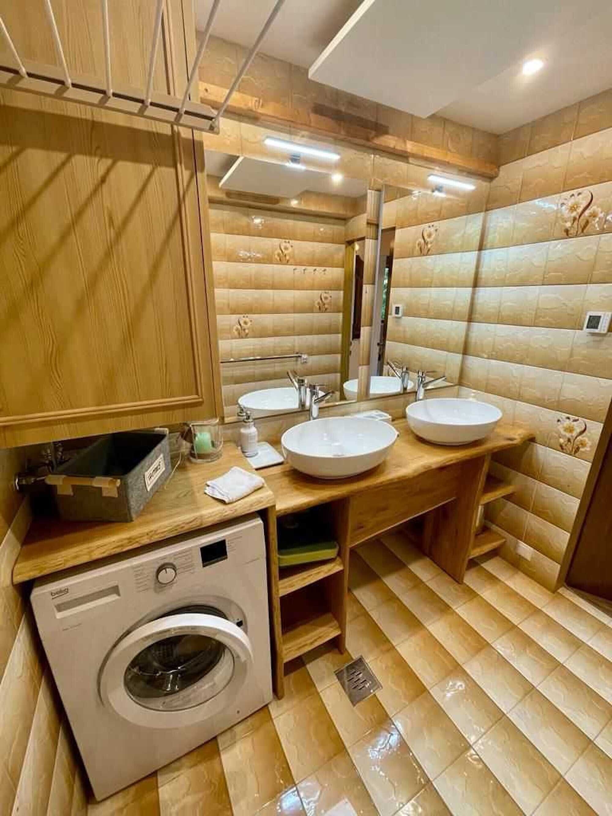 Un bagno moderno con due lavabi, uno specchio, una lavatrice e mobili in legno.