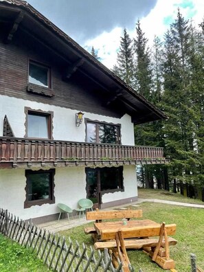 A two-story building with a balcony, wooden fence, and a picnic table. - Holiday Home 'Almhaus-Klippitz' with Direct Access to Ski Slopes, Garden & Wi-Fi (Wolfsberg)