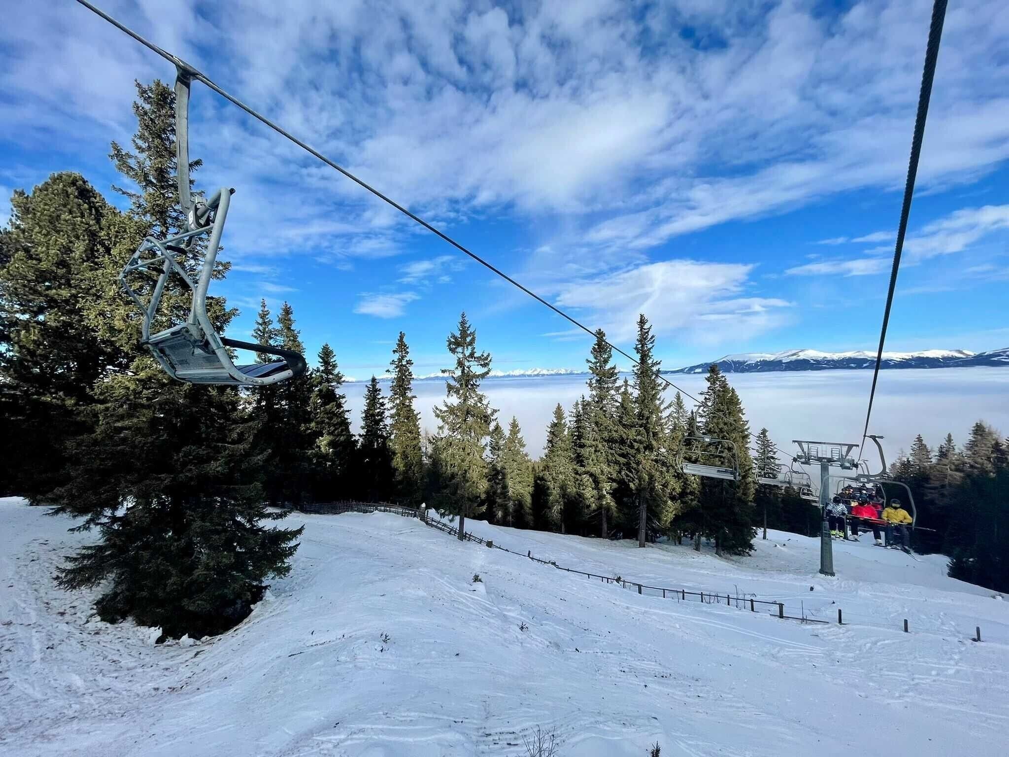 A ski lift with a clear view of snow-covered trees and a distant mountain range.