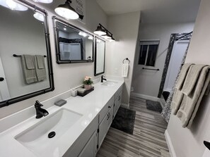 A modern bathroom with a white sink, two mirrors, and a shower area. - Lovely, Peaceful, and Modern Las Vegas Home! Close to Strip! (North Las Vegas)